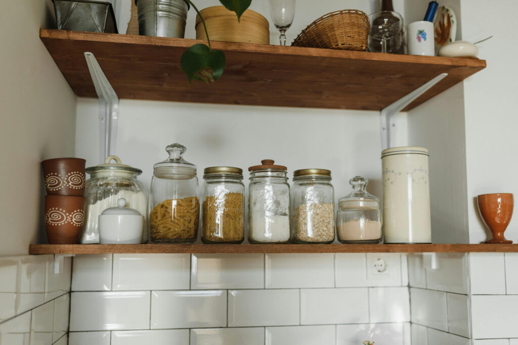 Farmhouse kitchen floating shelves with glass jars storing dry goods like pasta and grains