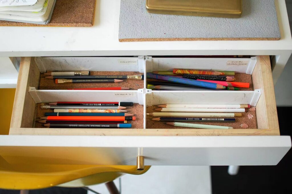 Neatly sorted colored pencils in a clear drawer organizer, showcasing a calm and efficient workspace.