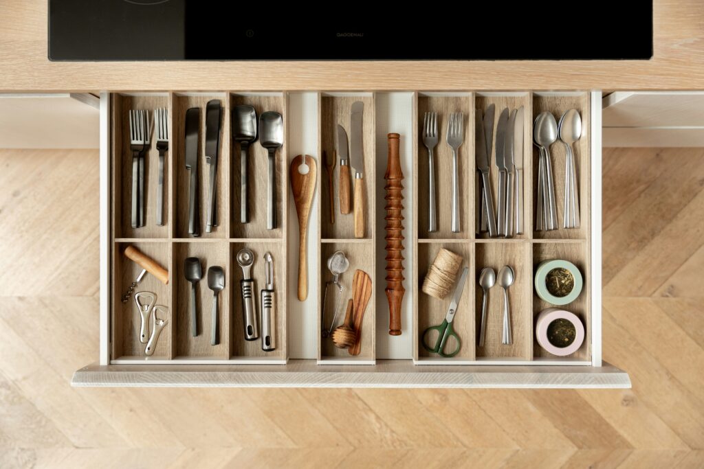 Adjustable drawer organizer with multiple compartments for kitchen utensils, demonstrating compartmentalization for closet and drawer organization