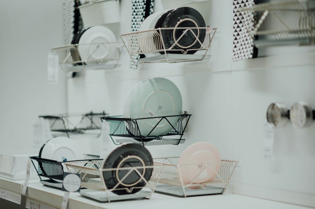 Multiple dish drying racks displayed in a showroom setting with various styles and materials
